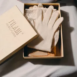 Witte handschoenen en beige accessoire in open doos met merklogo