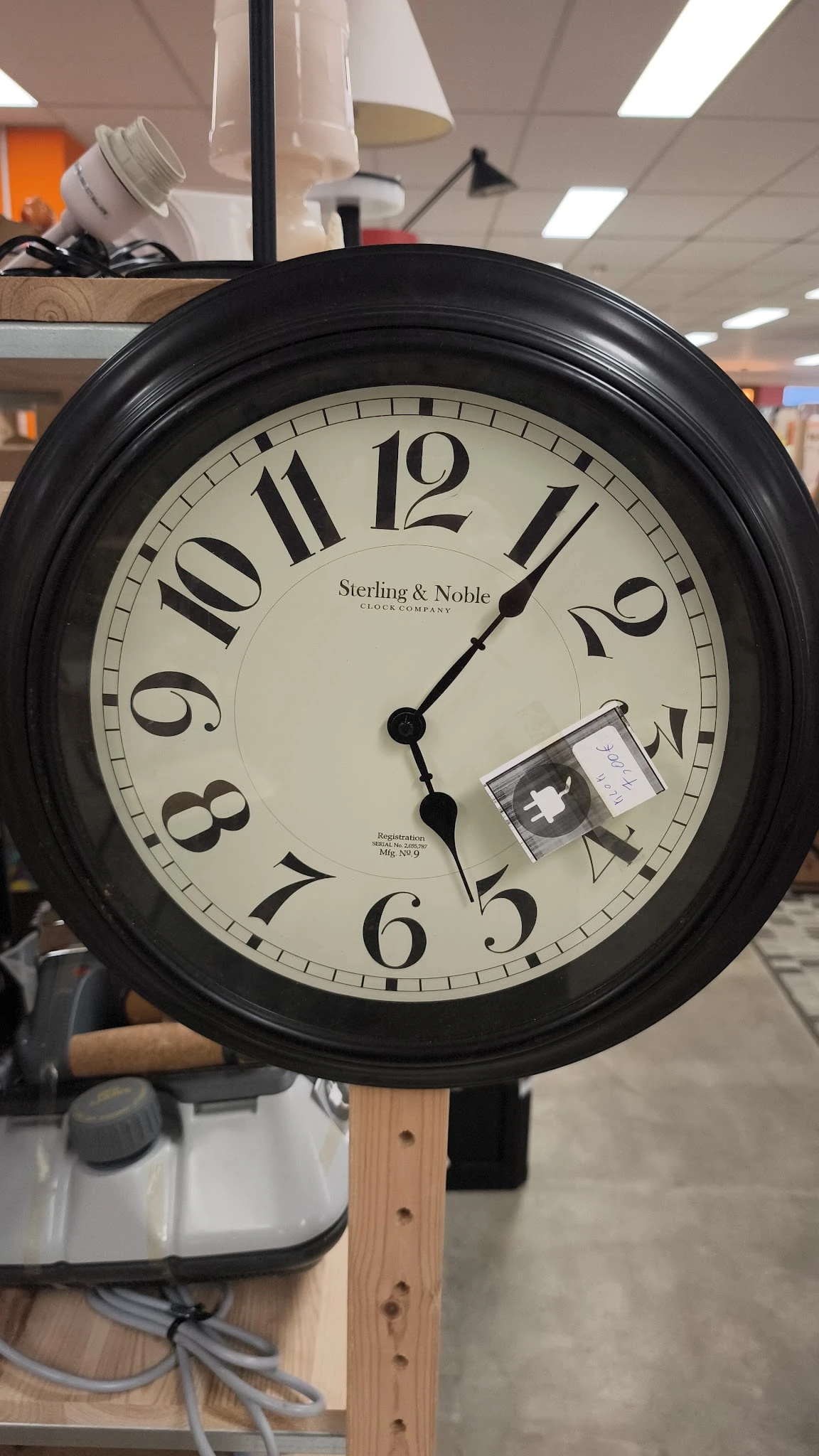 Zwarte wandklok Sterling & Noble met Romeinse cijfers, wijzers gericht op ongeveer 4 uur