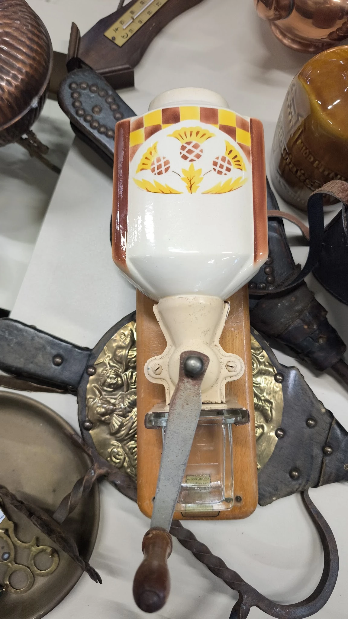 Close-up van een decoratief wandornament met gele veren, wit porselein en messingwerk