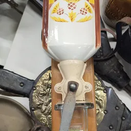 Close-up van een decoratief wandornament met gele veren, wit porselein en messingwerk
