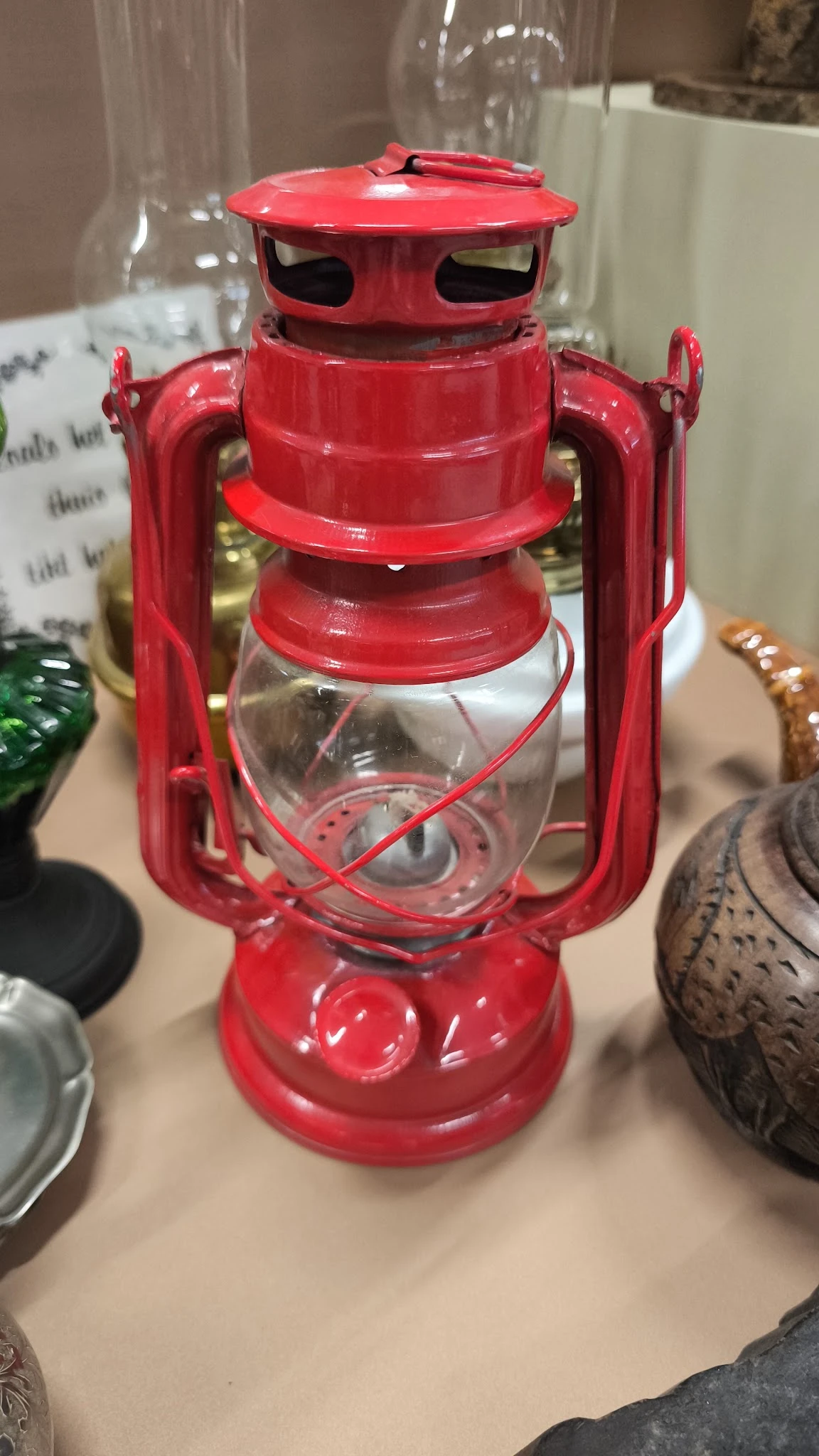 Close-up van een rode vintage campinglamp met glazen reservoir en hengsels