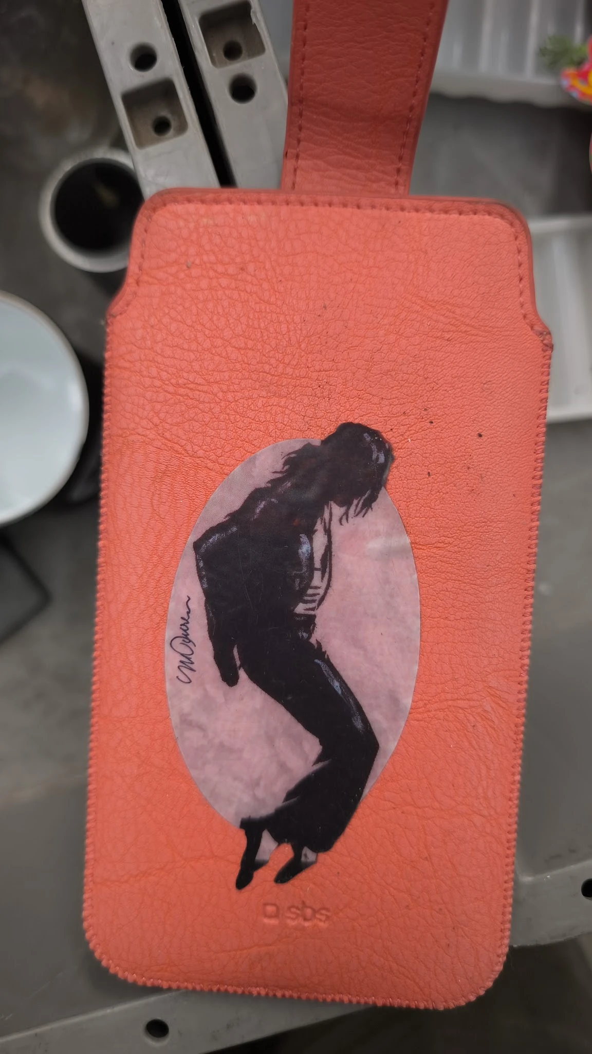 Close-up van een rood boek of object met een zwart-wit portretafbeelding van een persoon op het omslag