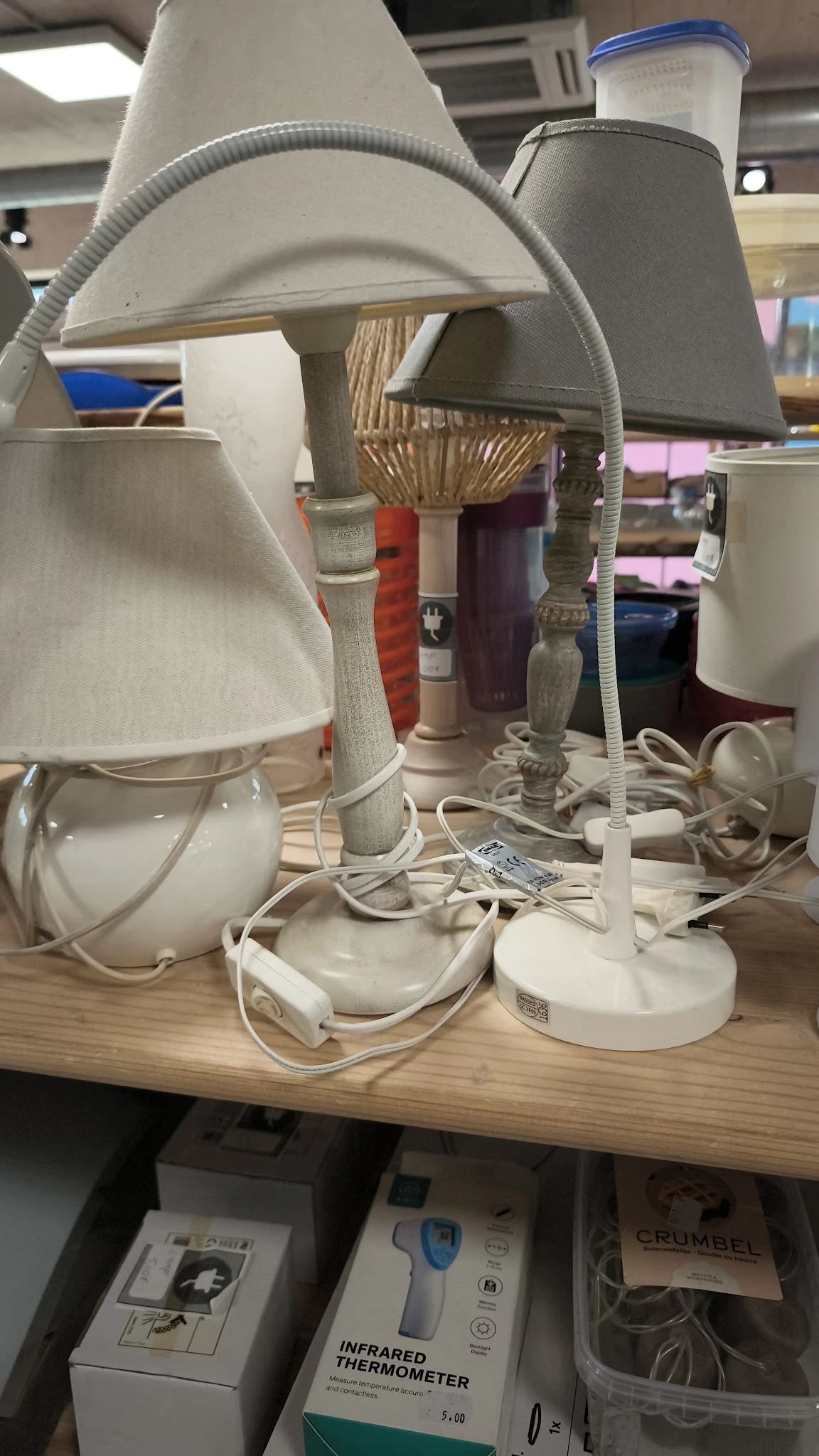 Verzameling van tweedehands tafellampjes met witte en gekleurde kapjes op een houten tafel