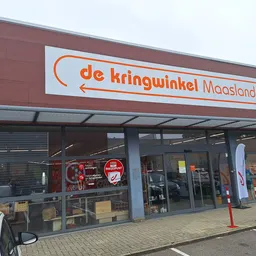 Voorgevel van kringloopwinkel met rood-bruine gevel, glazen pui en oranje logo met winzelnaam