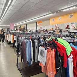 Rekken met kleding in verschillende kleuren in een kringloopwinkel