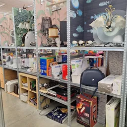 Stellingkasten met huishoudelijke artikelen, lampen, kastjes en diverse spullen in de kringloopwinkel