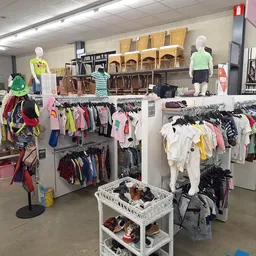 Winkelvloer met kledingrekken, mannequins en stapels tweedehands kleding in verschillende kleuren
