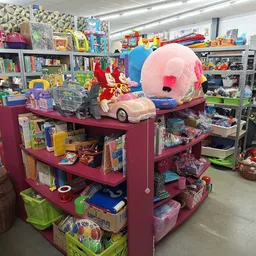 Winkelvloer met paarse stellingen vol speelgoed, boeken en diverse artikelen, grote roze speelgoedballon zichtbaar