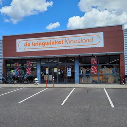 Gevel van kringloopwinkel met rode bakstenen voorgevel en daarop duidelijk zichtbare winkelnaam in oranje letters