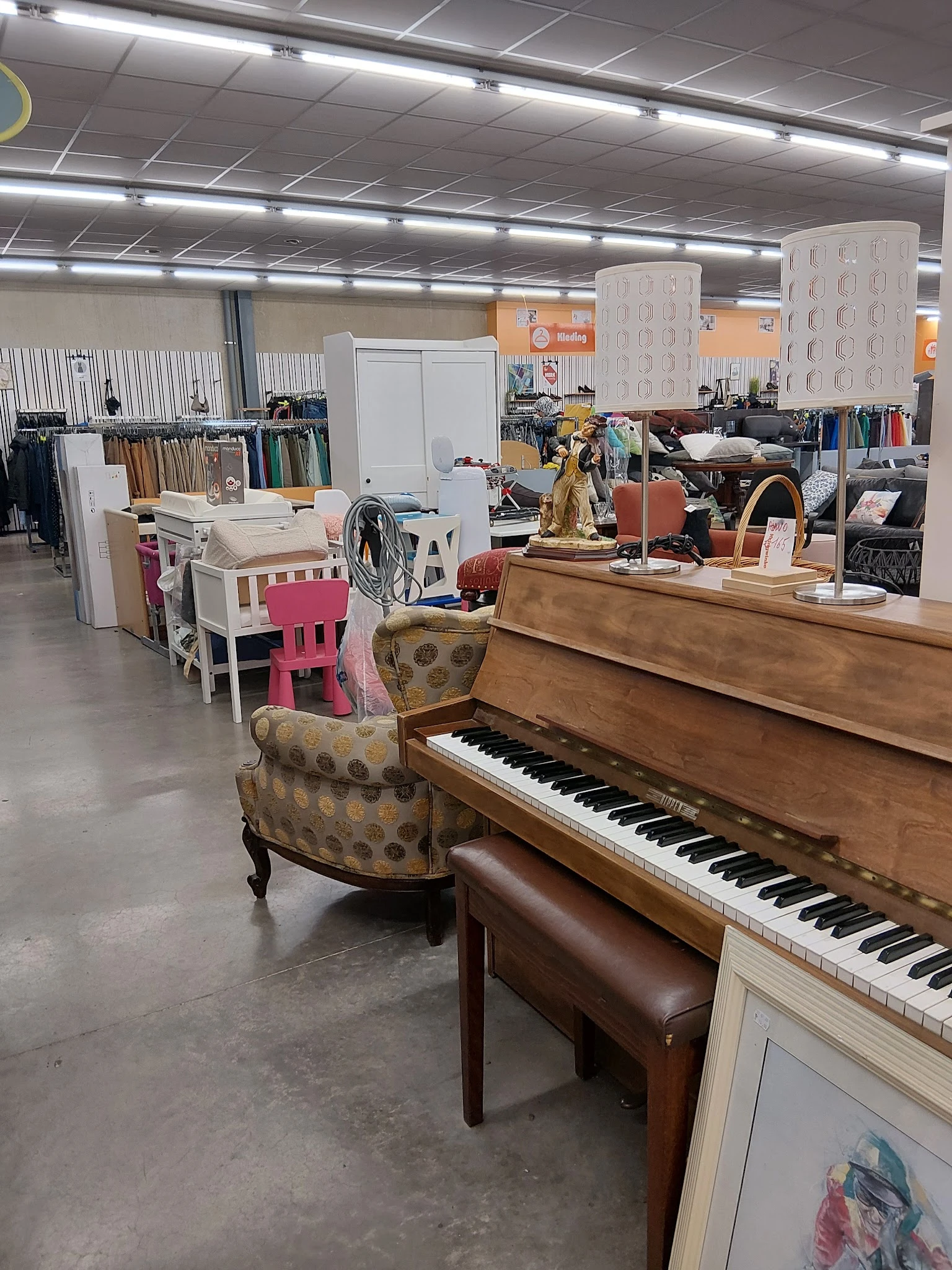 Winkelvloer met piano, fauteuil, meubels en diverse spullen in kringloopwinkel