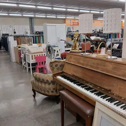Winkelvloer met piano, fauteuil, meubels en diverse spullen in kringloopwinkel