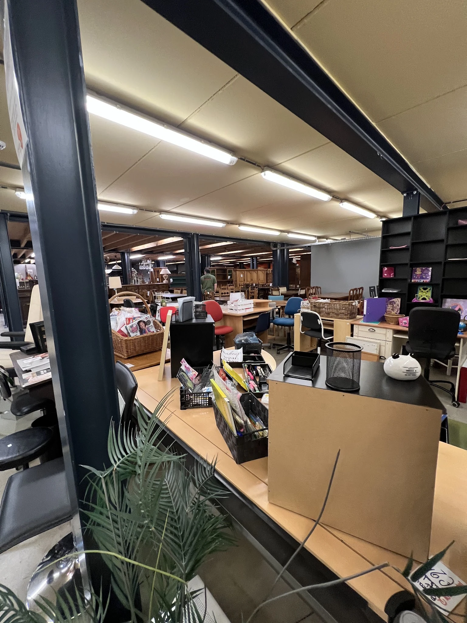 Winkelinterieur met werkplekken, stellingen, displaykasten en diverse tweedehandsartikelen op tafels en in bakken