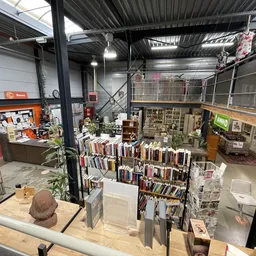 Overzicht van de winkelruimte met boekenrekken, stellingen en diverse spullen, gezien vanaf verhoogd punt
