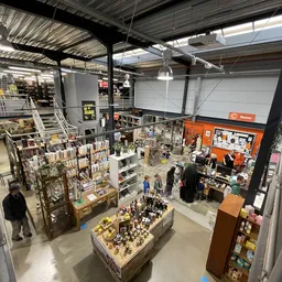 Overzicht van de winkelvloer met verschillende afdelingen, stellingen en uitgestalde spullen in een kringloopwinkel