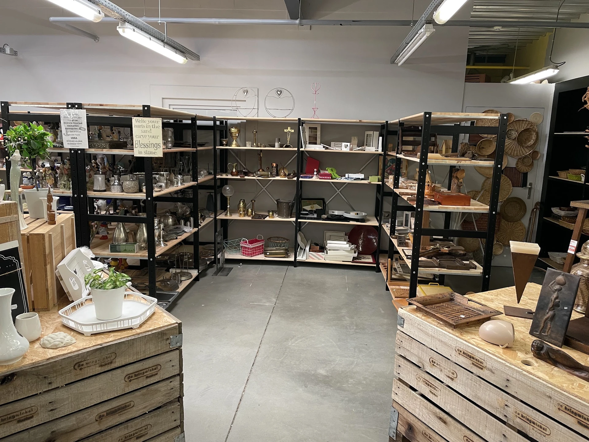 Winkelinterieur met zwarte stellingen vol met spullen, houten toonbanken aan beide zijden en heldere verlichting