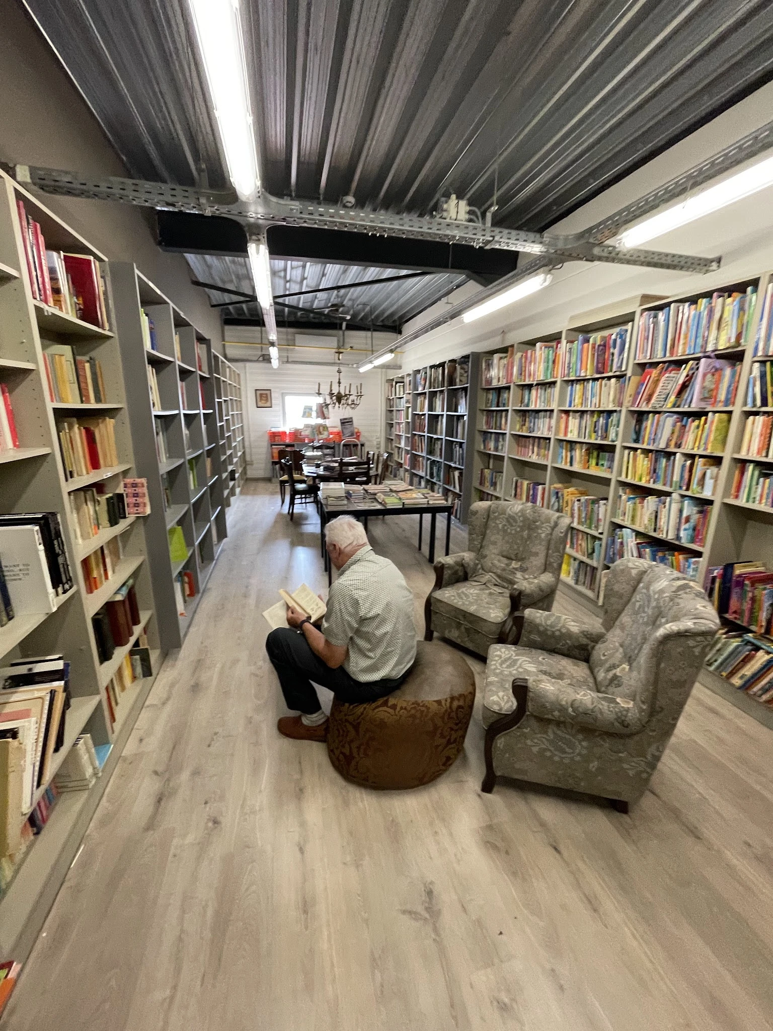 Leesgedeelte in kringwinkel met boekenkasten, leunstoel en man die leest