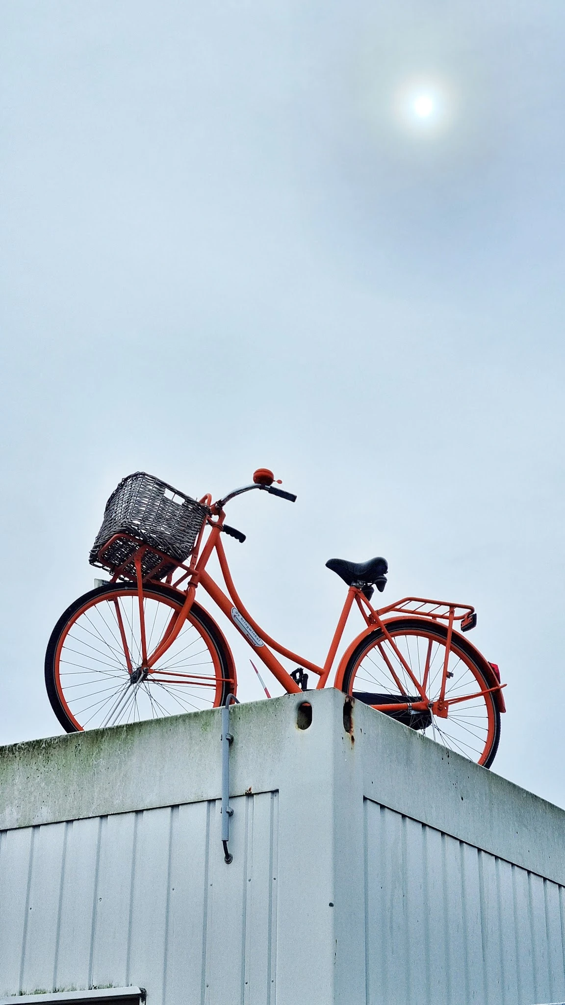 Rode vintage fiets met zwart mandje tegen hemel gefotografeerd