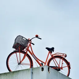 Rode vintage fiets met zwart mandje tegen hemel gefotografeerd