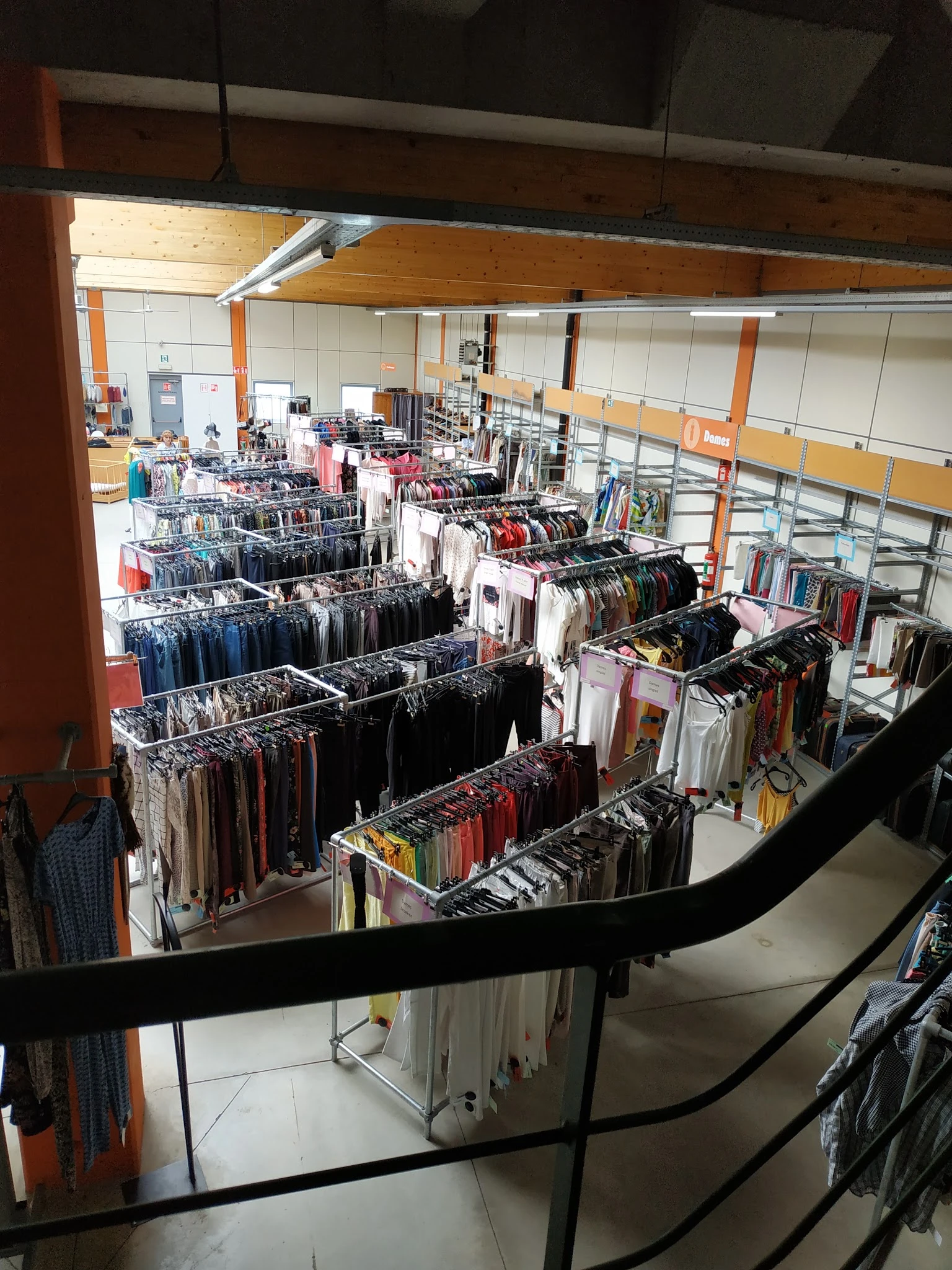 Overzicht van de winkelhal met talrijke rekken vol kleding, gezien vanaf een balkon of verhoogd platform