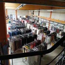 Overzicht van de winkelhal met talrijke rekken vol kleding, gezien vanaf een balkon of verhoogd platform