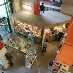 Overzicht van een kringloopwinkel met vitrines, stellingen en bezoekers op de winkelvloer