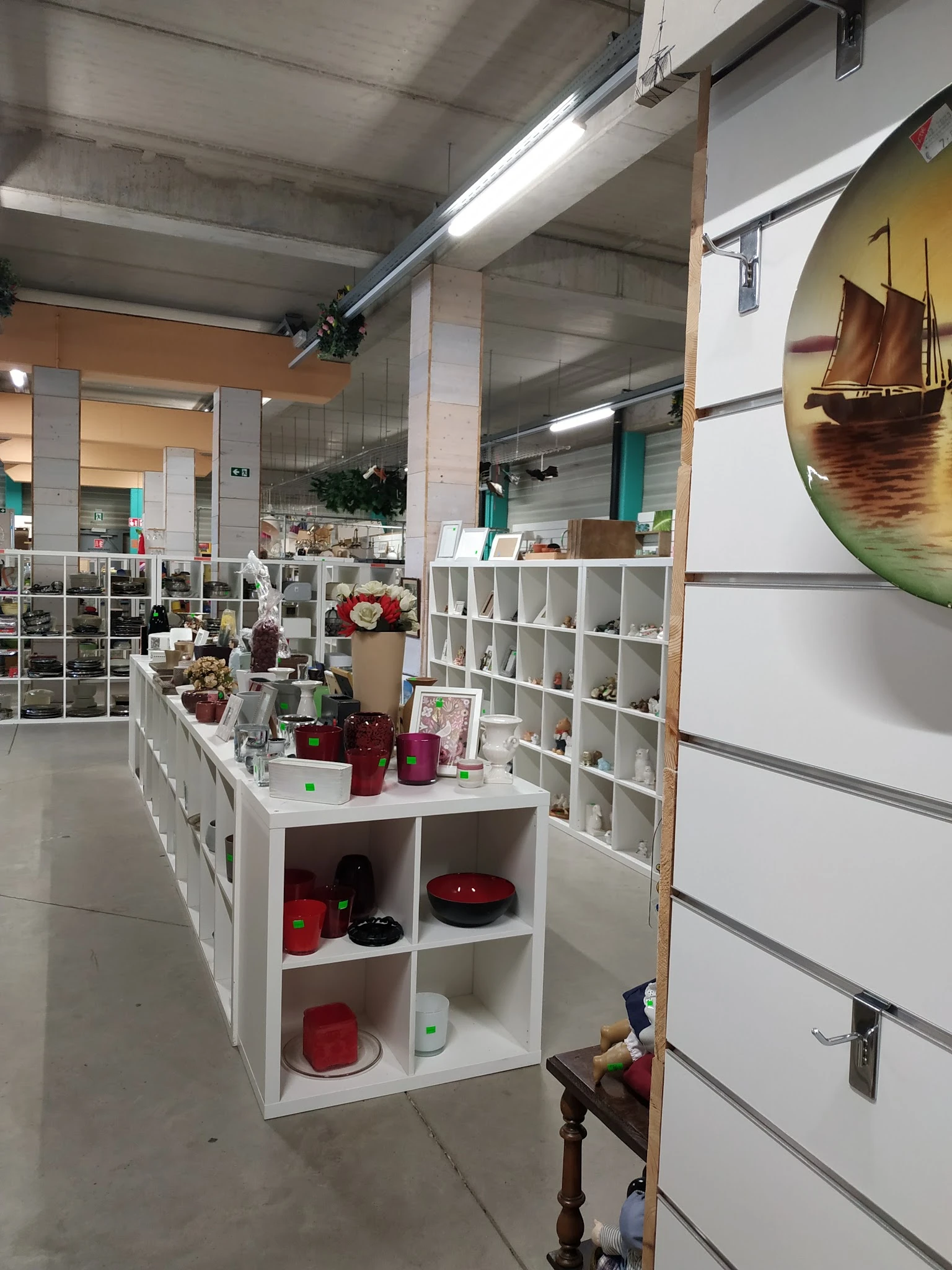 Winkelbinnenruimte met witte stellingen vol decoratieve artikelen, kaarsen en huisraad; overzicht van afdeling