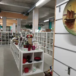 Winkelbinnenruimte met witte stellingen vol decoratieve artikelen, kaarsen en huisraad; overzicht van afdeling