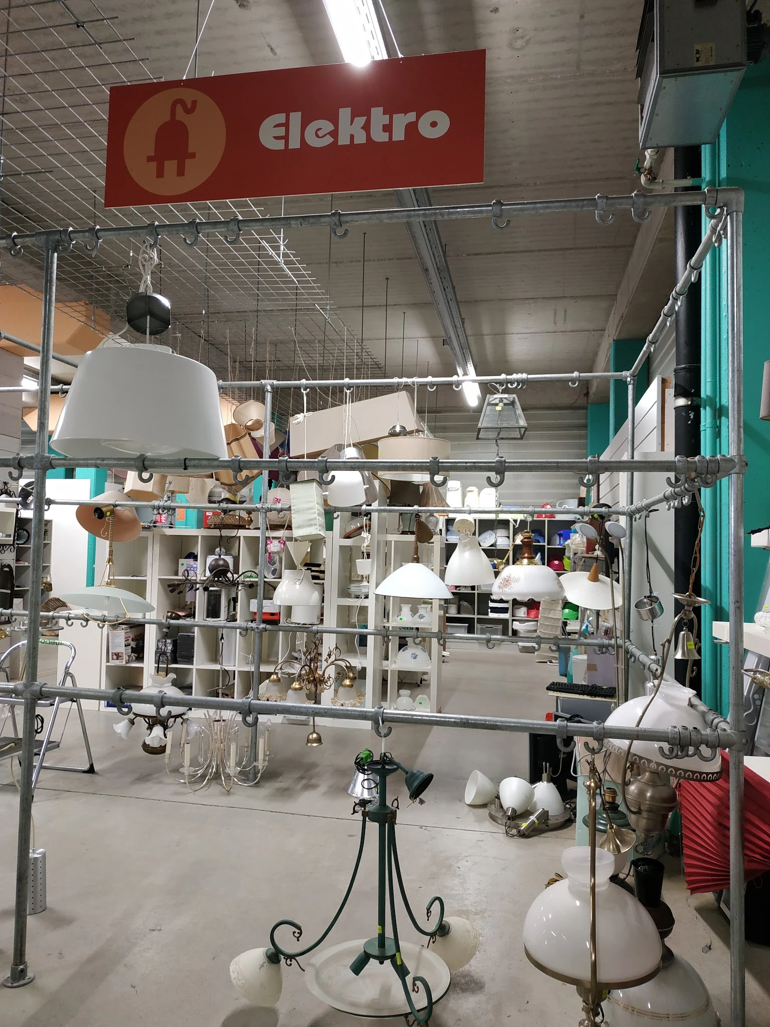Winkelbinnenruimte met hanglampen en stellingen vol spullen in een kringloopwinkel