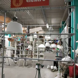 Winkelbinnenruimte met hanglampen en stellingen vol spullen in een kringloopwinkel