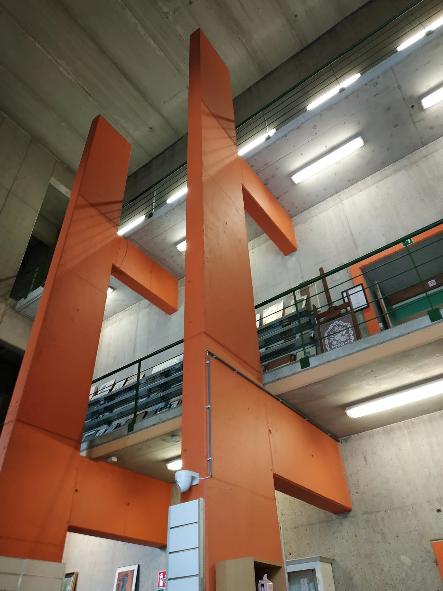 Interieur van kringloopwinkel met oranje stalen zuilen, galerijverdiepingen en fluorescente verlichting