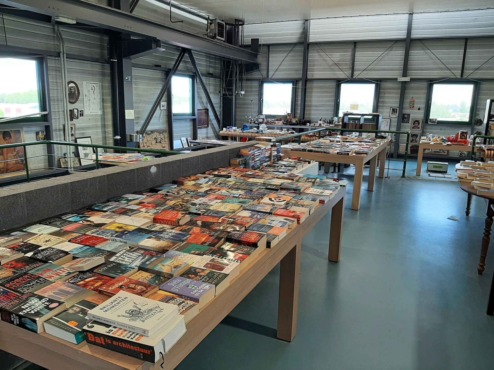 Grote tafel vol met tweedehands boeken en dvd's uitgestald in een kringloopwinkel