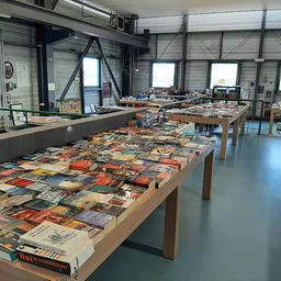 Grote tafel vol met tweedehands boeken en dvd's uitgestald in een kringloopwinkel