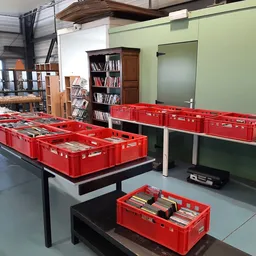 Rode kunststof kratten met boeken uitgestald op tafels in de winkel