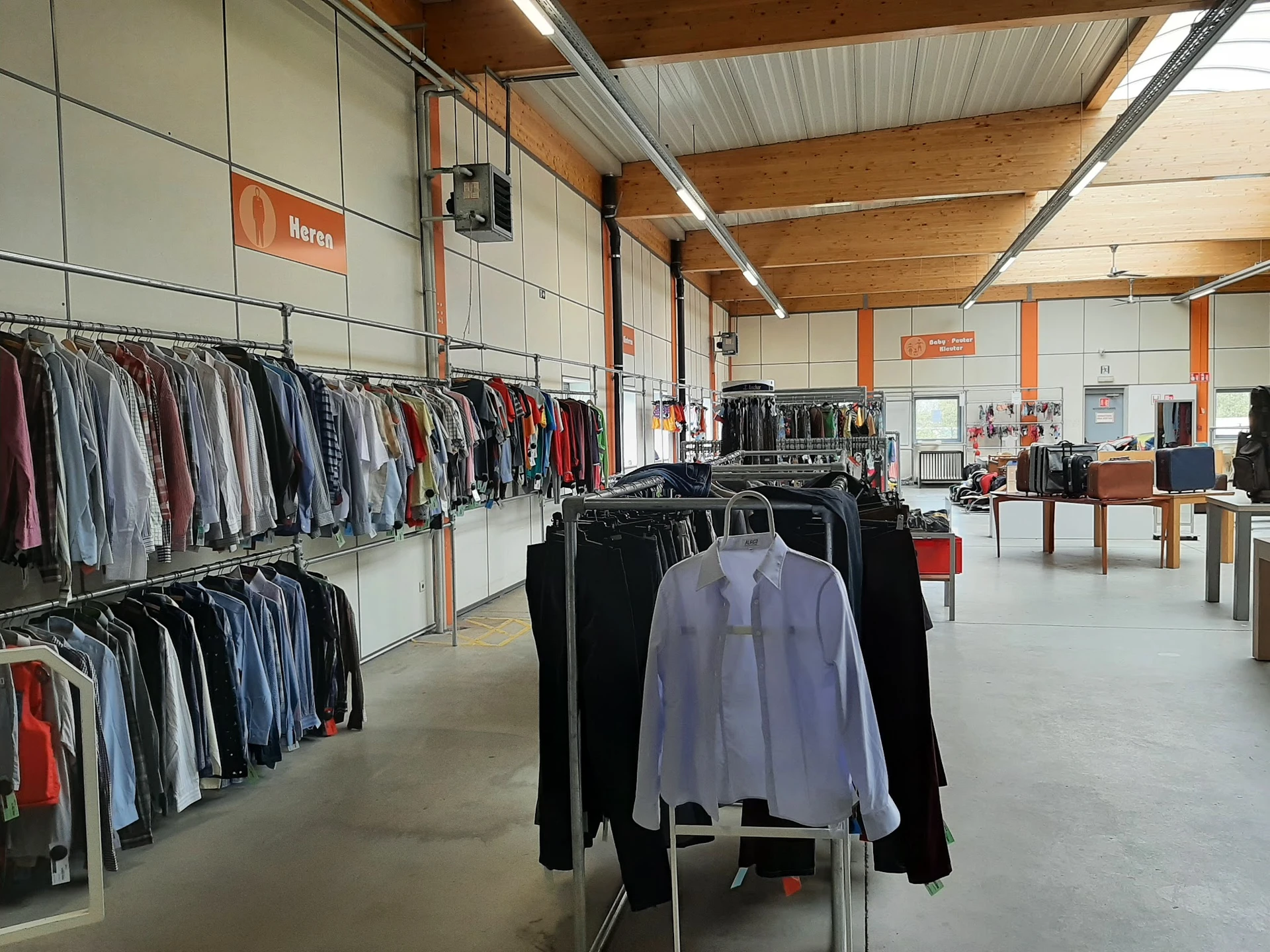 Winkelinterieur met kledingrekken en uitgestalde kleding in een kringloopwinkel