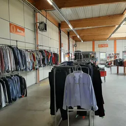 Winkelinterieur met kledingrekken en uitgestalde kleding in een kringloopwinkel