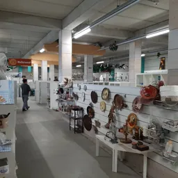 Winkelruimte met display aan rechtermuur met kookgerei en potten, stellingen met artikelen, betaalbalies op achtergrond