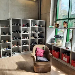 Winkelinterieur met schoenensorteerkasten, een bruine fauteuil en rood opbergmeubilair