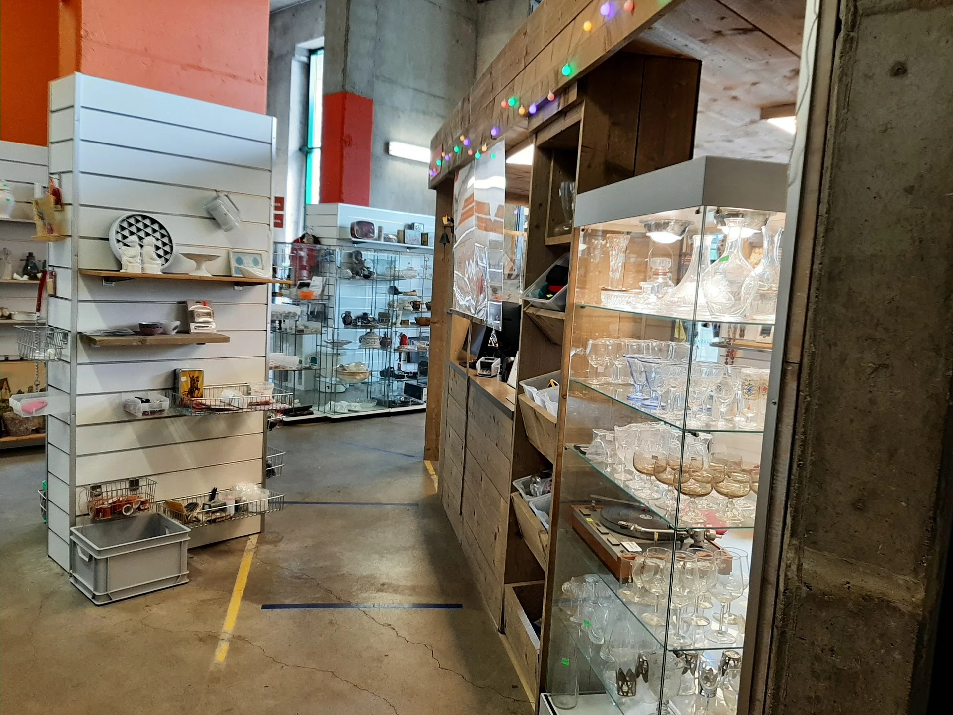 Winkelvloer met stellingen en vitrines vol tweedehandsartikelen in kringloopwinkel