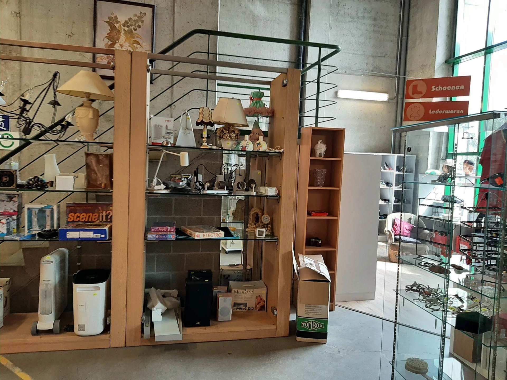 Houten display-meubel met glazen deuren vol decoratieve items, fotolijsten en huishoudartikelen in tweedehandswinkel