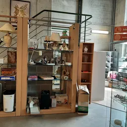 Houten display-meubel met glazen deuren vol decoratieve items, fotolijsten en huishoudartikelen in tweedehandswinkel