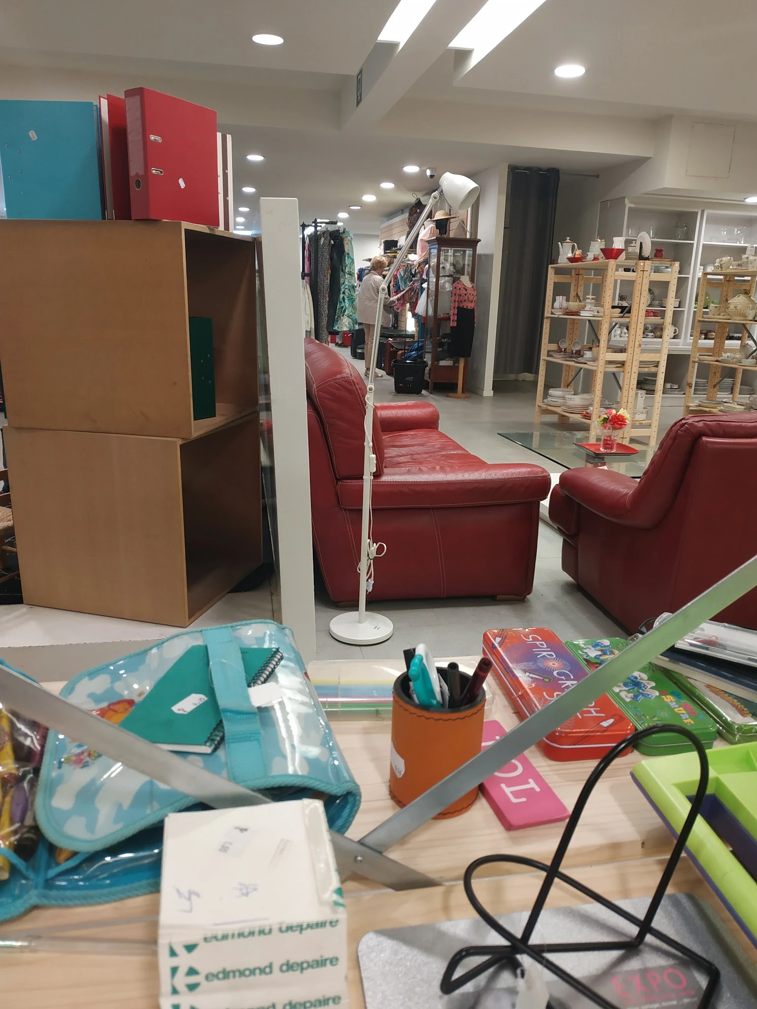 Winkelinterieur met rode fauteuils, houten kast, stellingen met spullen en voorraad op tafel
