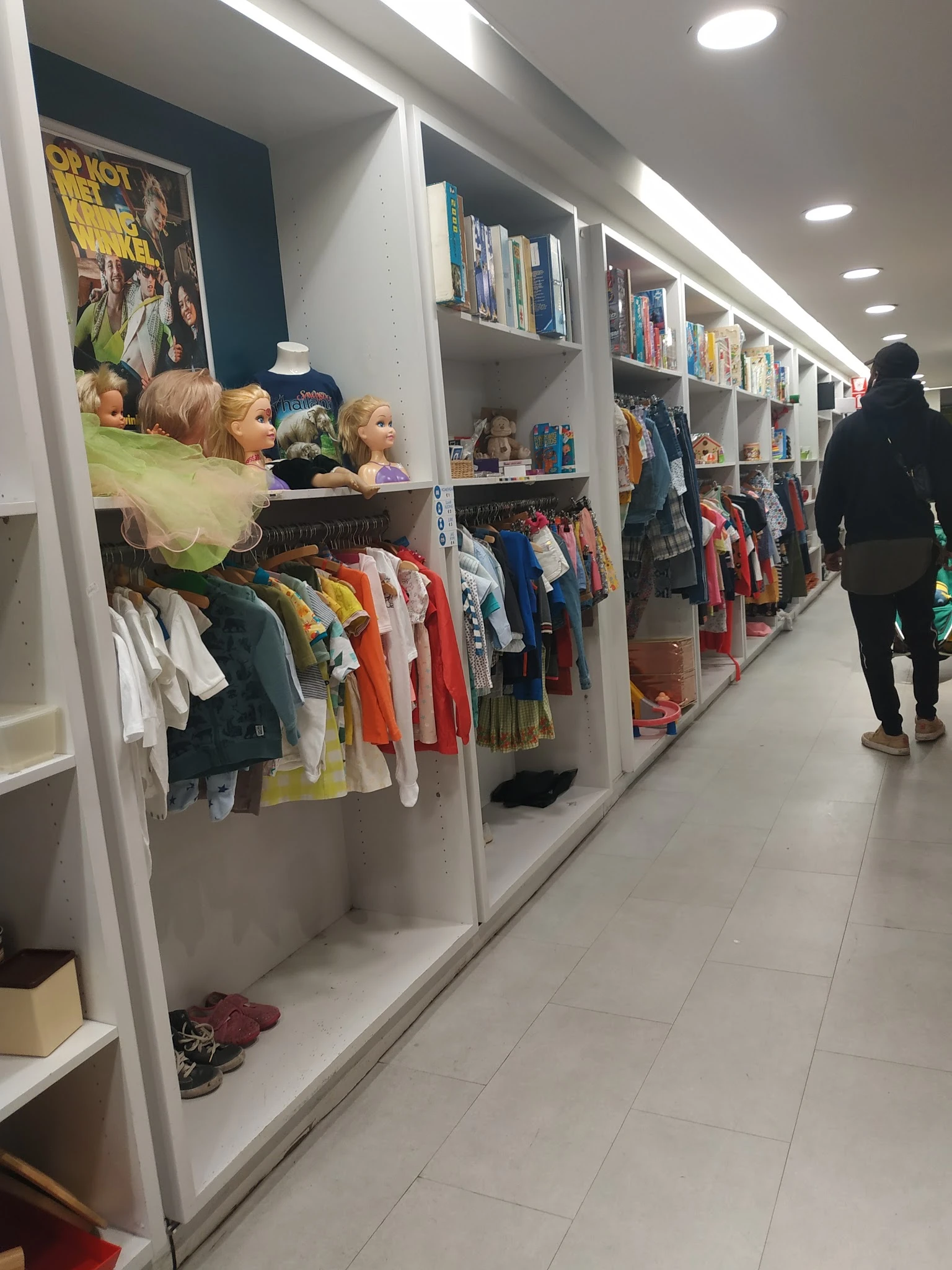 Rekken met kinderkledingaanbod in verschillende kleuren en maten in de kringloopwinkel