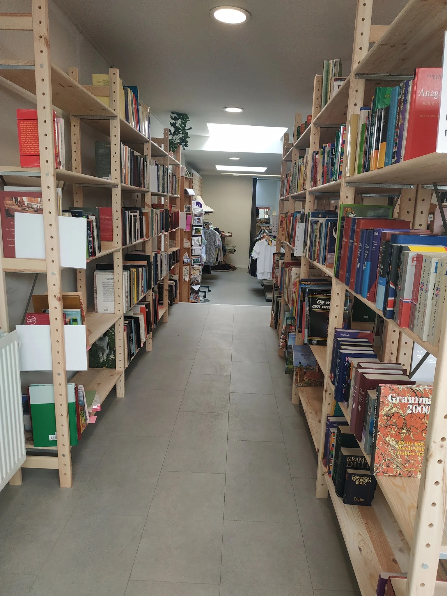 Gangpad tussen houten stellingen vol boeken in een kringloopwinkel