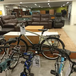 Tweedehandsfietsenen fietsen op de winkelvloer met bruine zitmeubels op de achtergrond