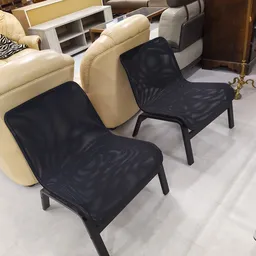 Twee zwarte modern design stoelen met mesh zitting en zwart stalen frame naast crèmekleurige bank