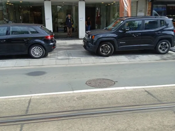 Straatvoorgevel met twee geparkeerde auto's en winkelentree met witte zuilen