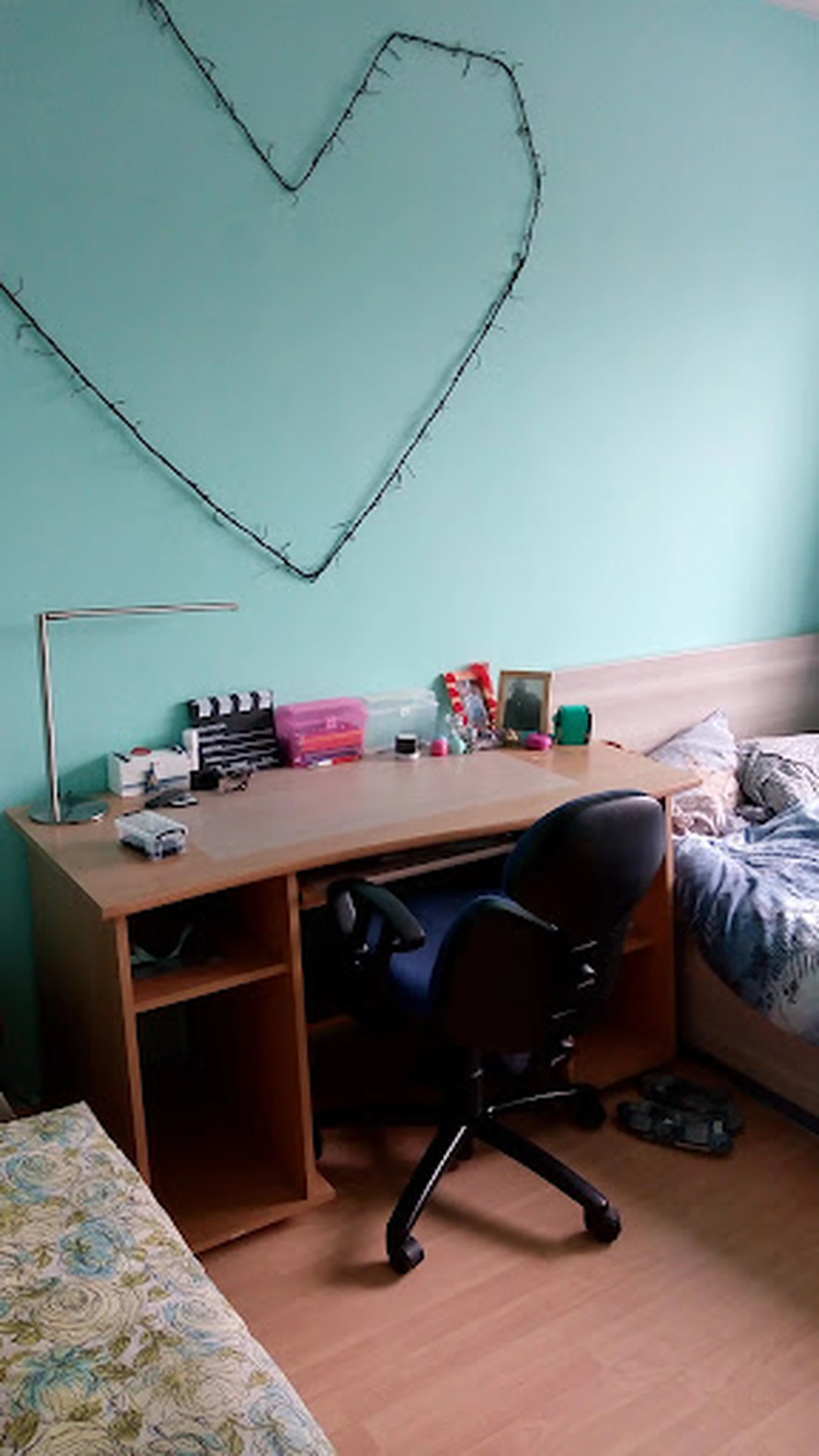 Werktafel met diverse spullen en voorraad in een kamer met turquoise muur en roze deur