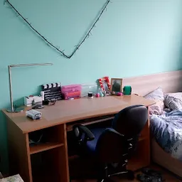 Werktafel met diverse spullen en voorraad in een kamer met turquoise muur en roze deur