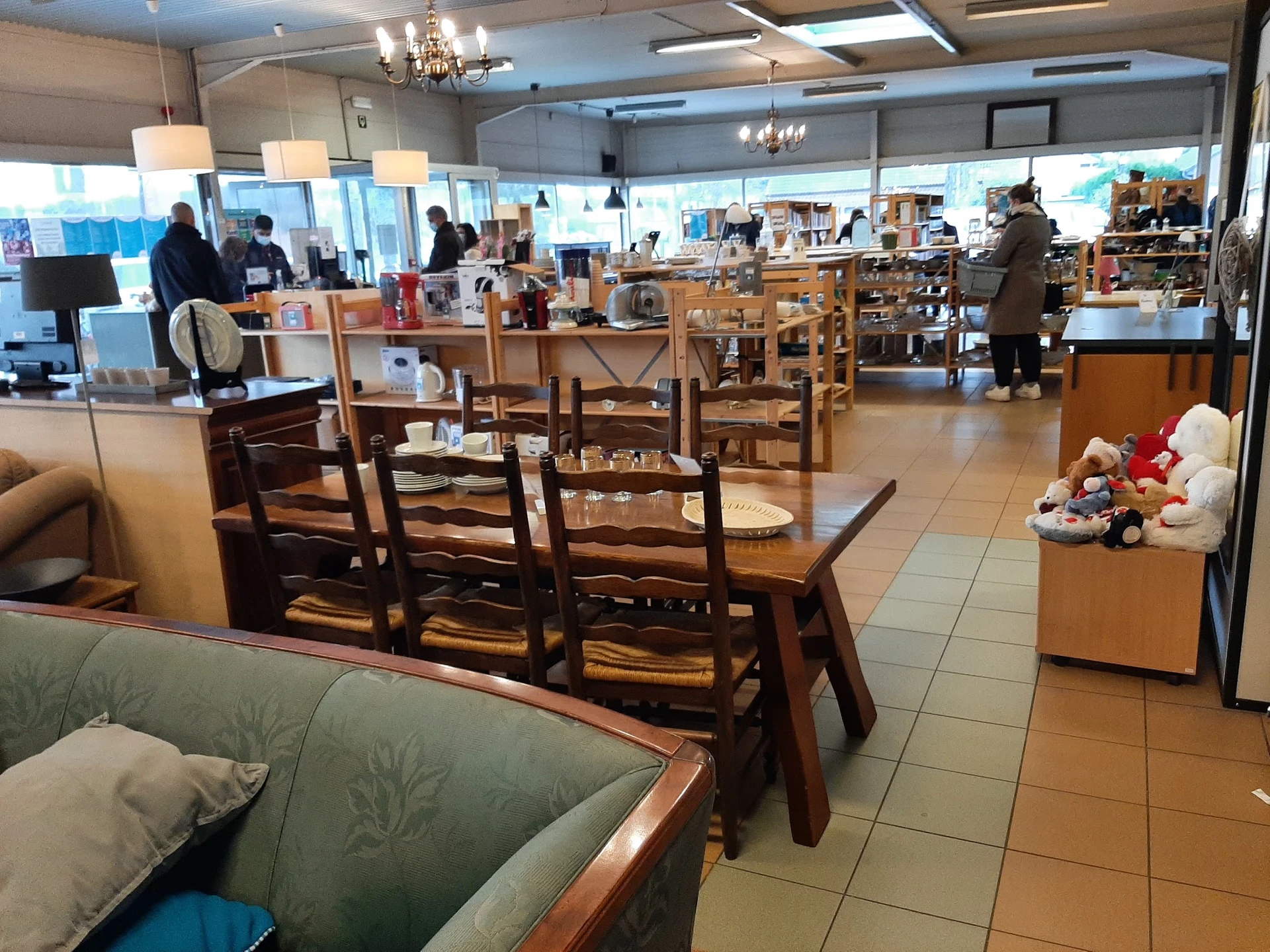 Ruim winkelbinnenruimte met houten meubels, stoelen en tafels, enkele bezoekers, moderne verlichting en grote ramen
