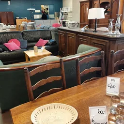 Winkelvloer met houten eettafel, stoelen, zwarte leren bank en houten meubelen in de achtergrond